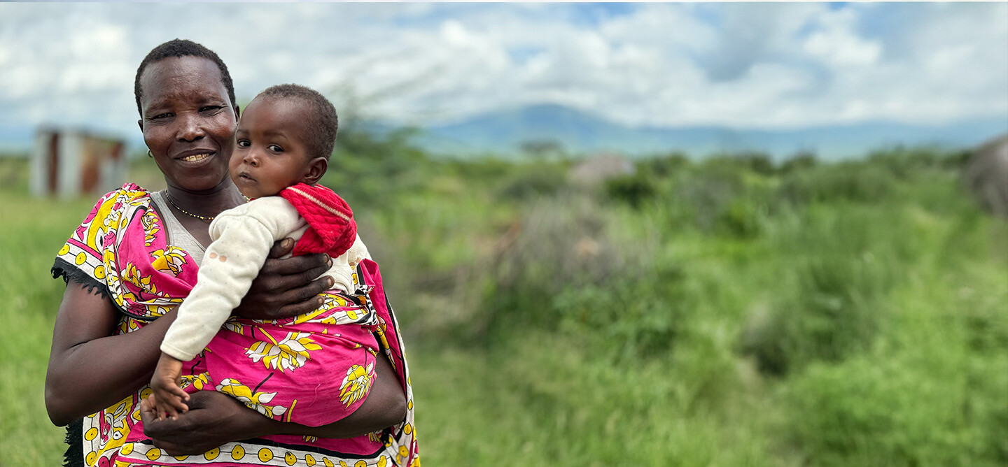 Woman holds child in a field